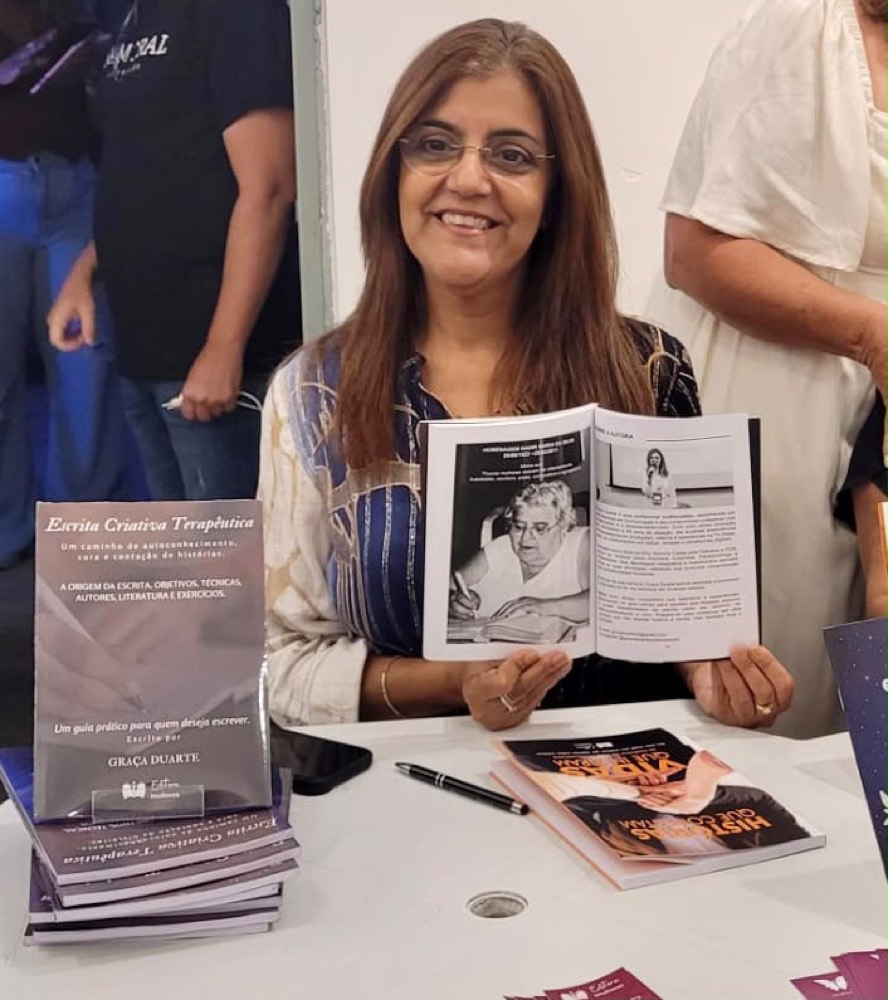 Graça Duarte sorrindo com seus livros em uma sessão de autógrafos
